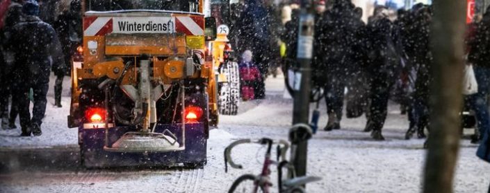 Winterfahrzeug streut in der Stadt einen Fußweg