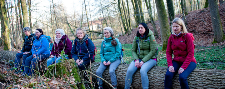 Waldbaden: Frauen mit geschlossenen Augen auf Baumstamm sitzend
