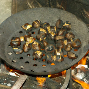 Geröstete Esskastanien in einer Eisenpfanne über Feuer