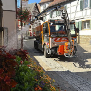 Ein Bewässerungsfahrzeug gießt Blumen in einem Beet. © EineStadt